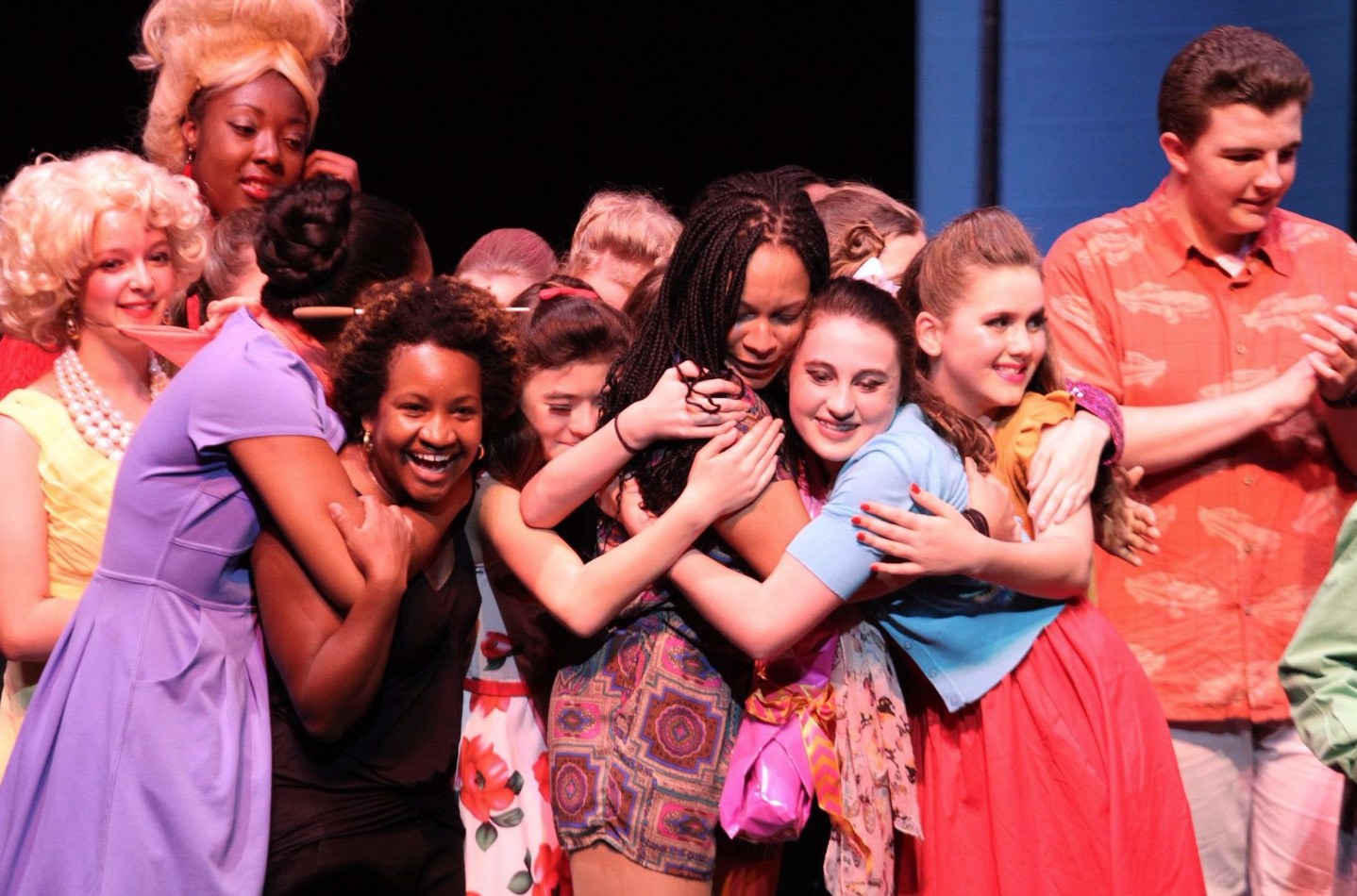 Close-up of an interracial group of kids hugging after performance