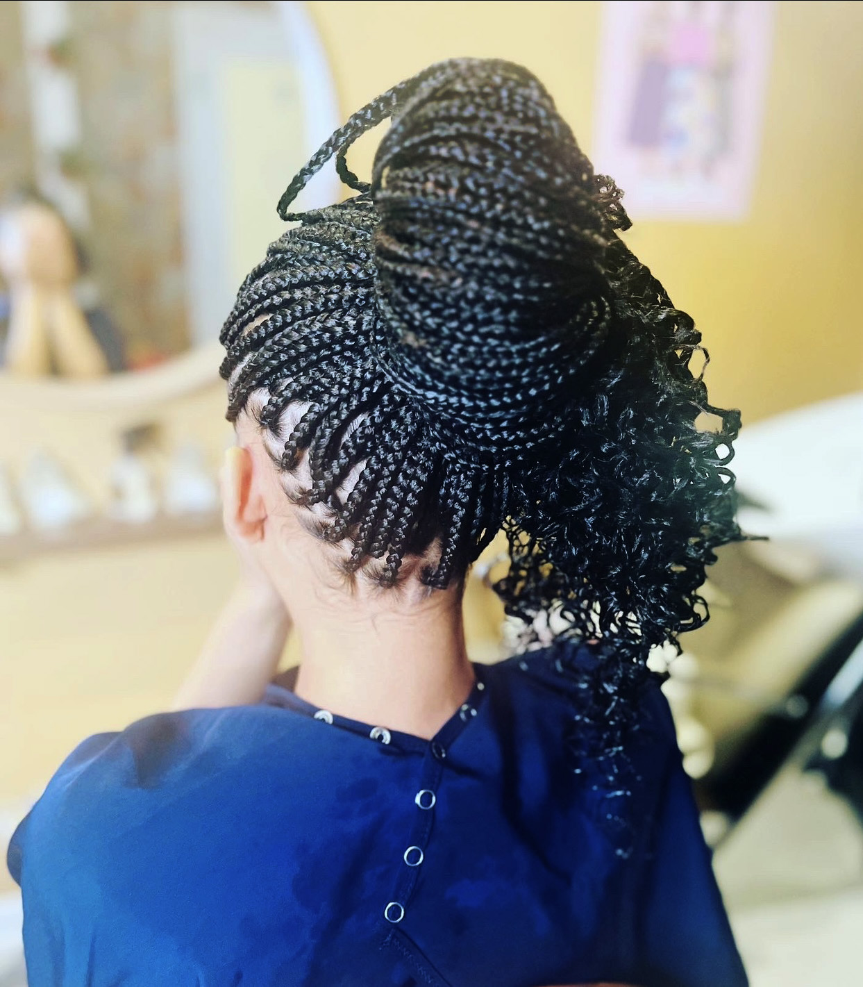 Long African braids tied on top of girl's head seen from back