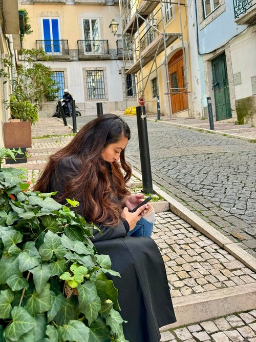 Young woman sitting on doorsteps and looking at her phone