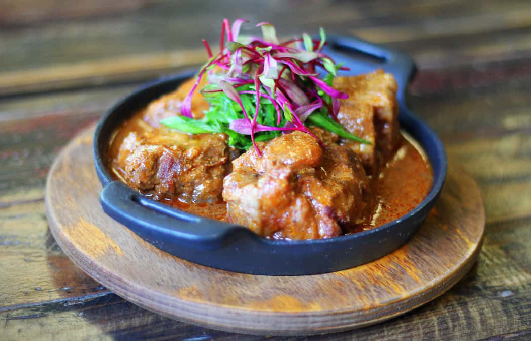 Caribbean dish in an iron pan on a wooden tray