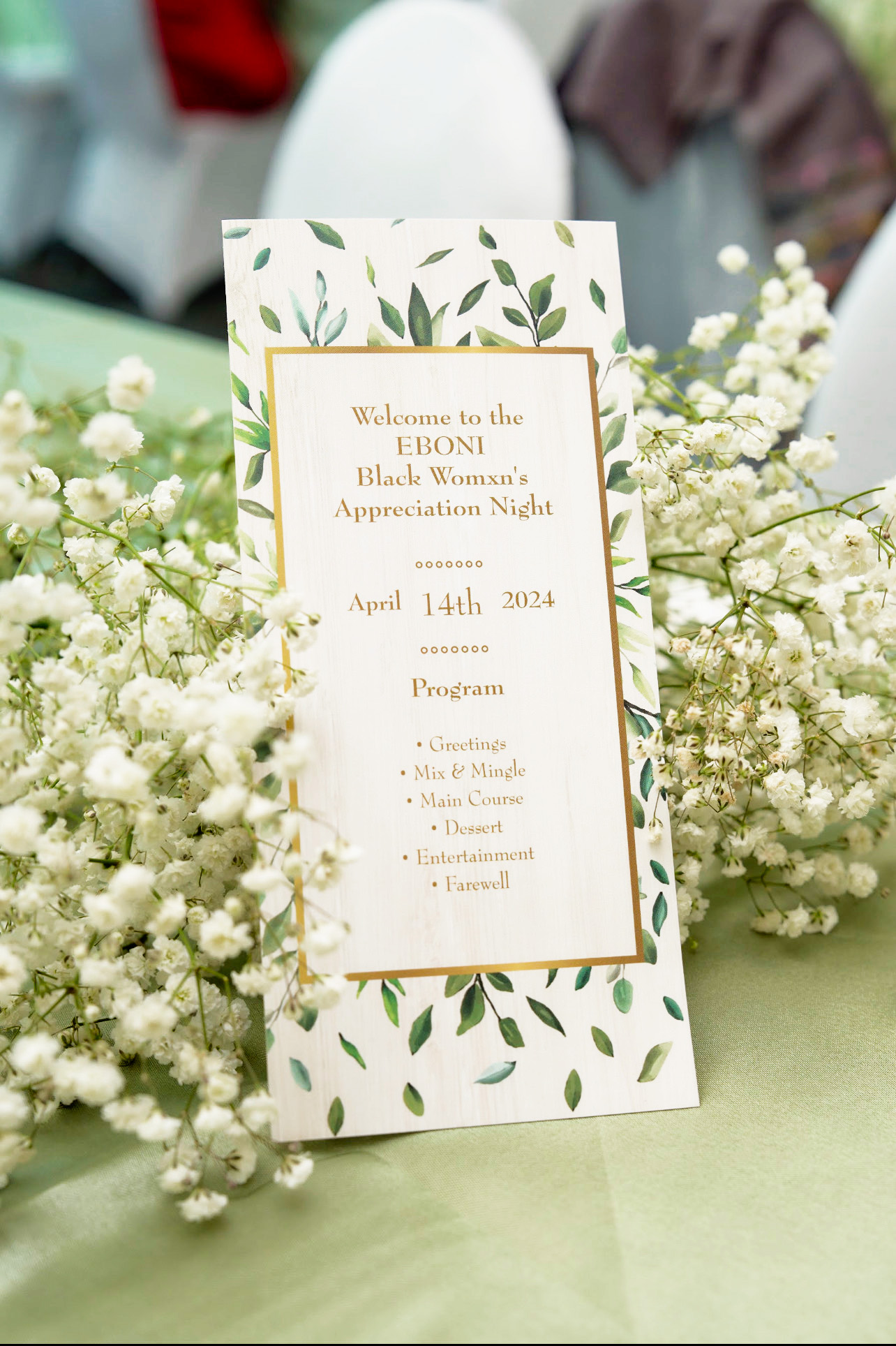 Invitation card on party table and surrounded by little white flowers