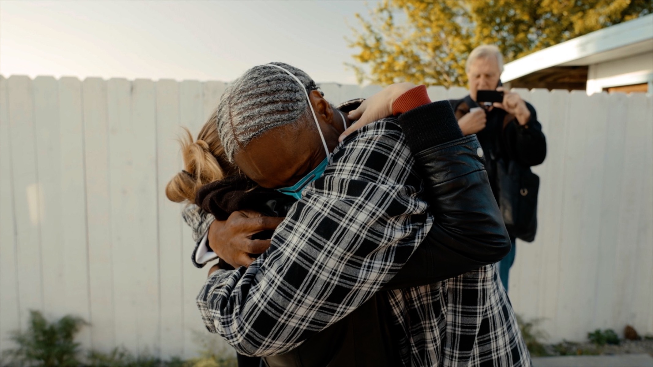 Emotional embrace of a man and a woman. Mask wears a COVID mask, woman's face is not showing i