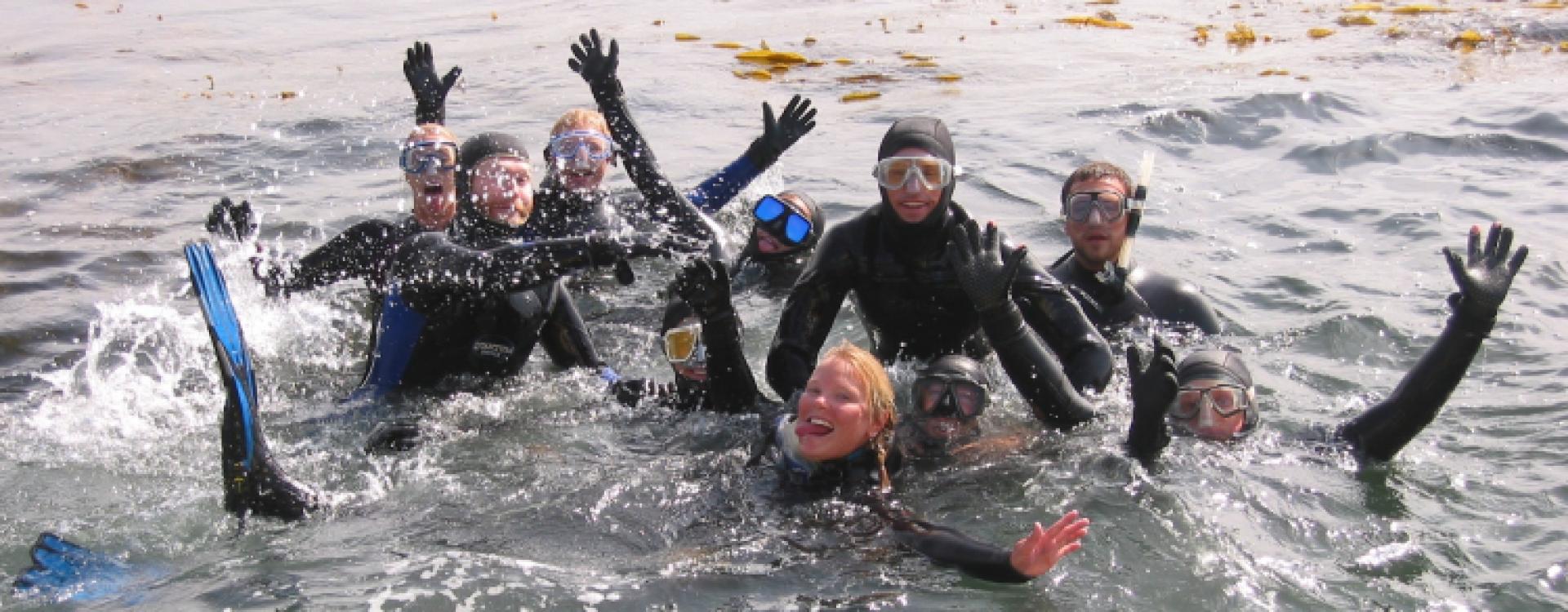 Young scuba divers in water waving at camera