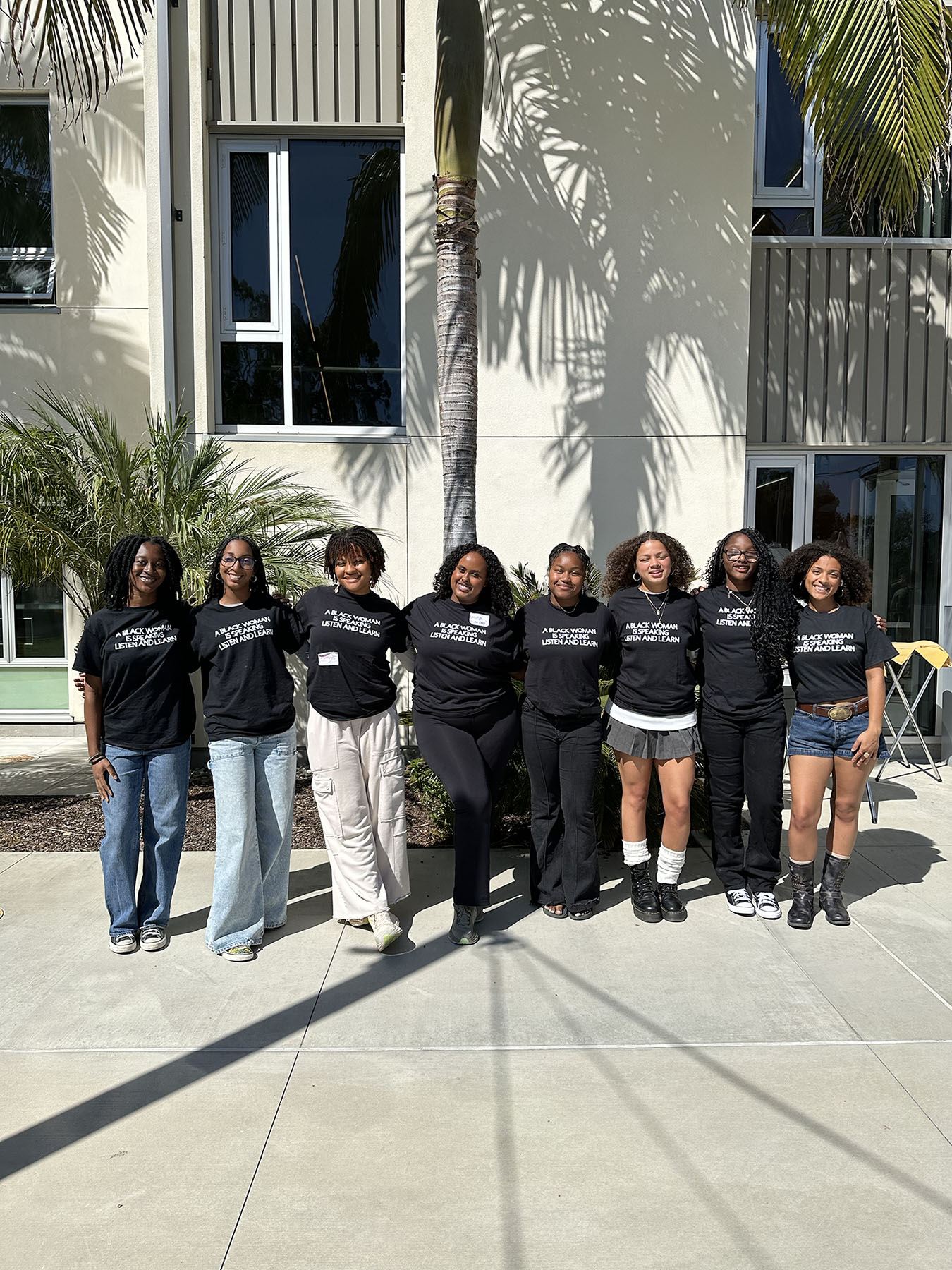 Group of 8 female students standing and showing their BWHC T-shirt