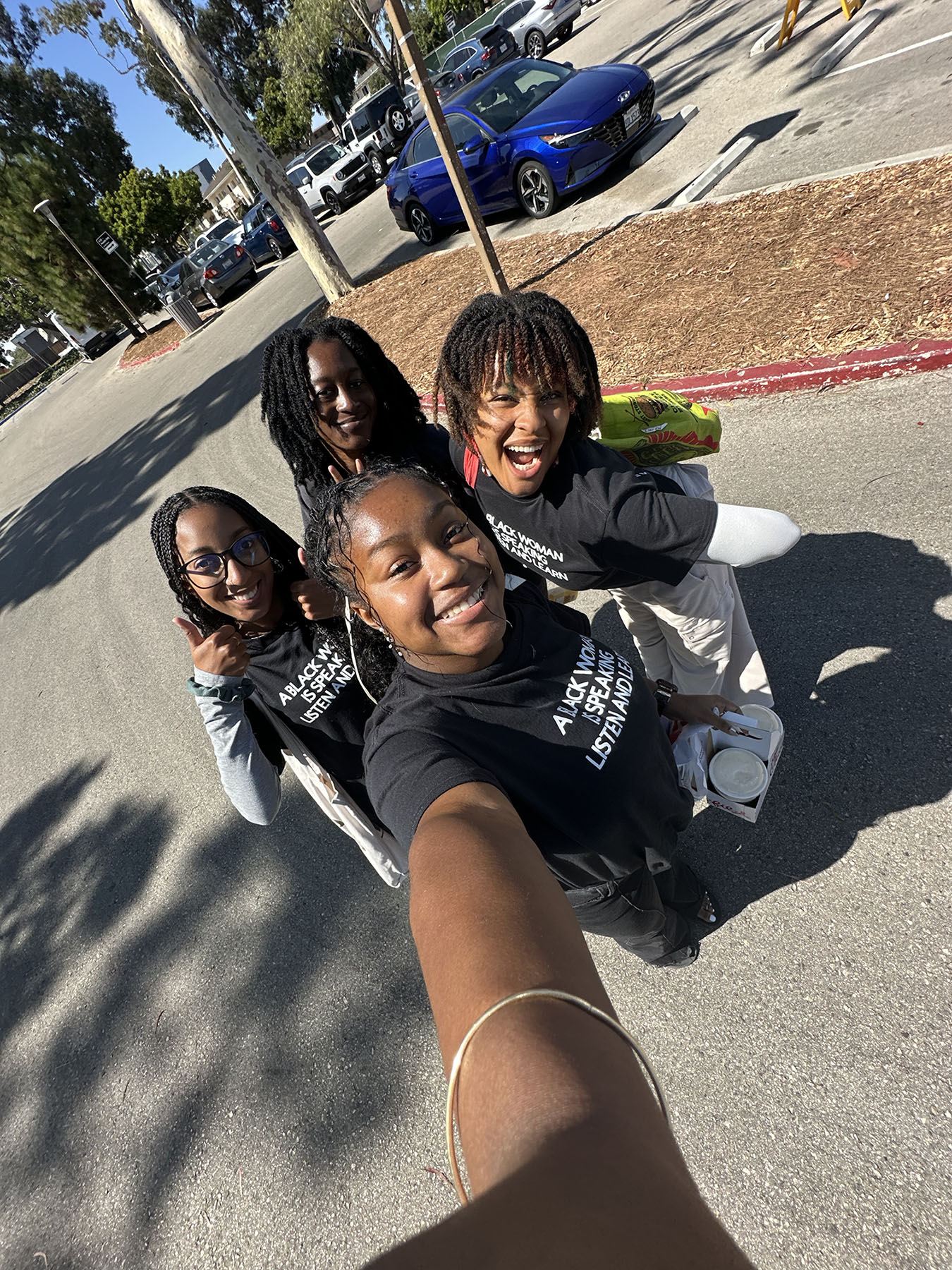 Selfie of 4 female students wearing the bwhc T-shirt