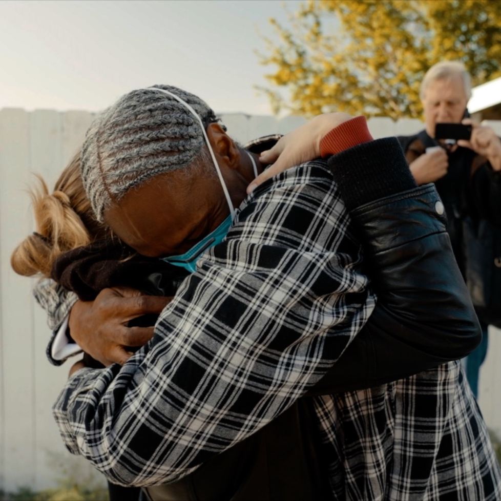 Emotional embrace of a man and a woman. Mask wears a COVID mask, woman's face is not showing i